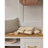 Beige Skip Hop silicone pacifier holder with strap, next to a matching changing pad and quilted bag.