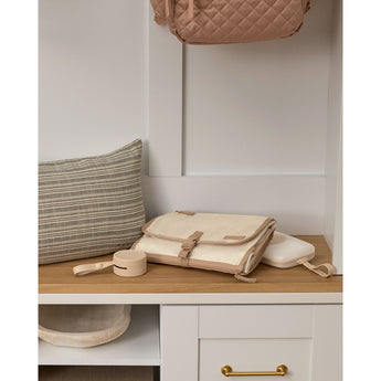 Beige Skip Hop silicone pacifier holder with strap, next to a matching changing pad and quilted bag.