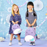 Two smiling toddlers hold purple Skip Hop Zoo Narwhal mini backpacks with iridescent fins.