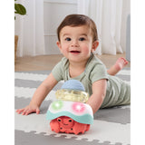 Smiling baby on a gray and white mat playing with a colorful Skip Hop Stack & Crawl 4-in-1 Crab toy.