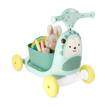 Mint green Skip Hop Zoo 3-in-1 hedgehog ride-on toy with yellow wheels, holding a plush bunny and crayons.