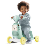Happy toddler riding a mint green Skip Hop Zoo 3-in-1 hedgehog ride-on toy with yellow wheels.