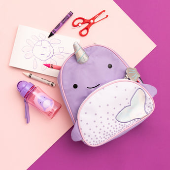Purple Skip Hop Zoo Narwhal mini backpack with iridescent horn and tail, water bottle, crayons, and scissors.