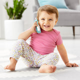 Happy baby playing with a light blue and white Skip Hop Zoo Phone with a unicorn horn.
