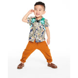 Smiling toddler boy wearing a green Skip Hop Zoolet Bee mini backpack with light blue straps.