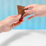 Hands holding a brown, textured, waffle-style ice cream cone against a blue striped background.