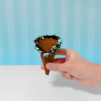 Hand holding a brown ice cream cone filled with chocolate slime and colorful sprinkles.