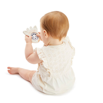 Baby in a white romper playing with a Sophie la girafe Magic Mirror SIGHT white teething toy.