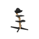 Stokke Nomi high chair with natural wood stem and black seat, back, footrest, and base.