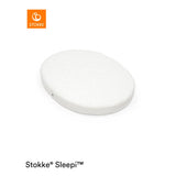 White oval Stokke Sleepi Mini polyurethane foam mattress pad with quilted top.