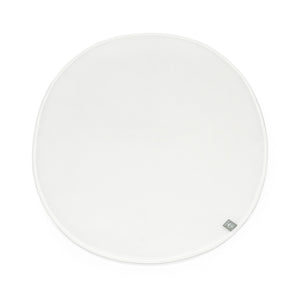 White circular Stokke Sleepi Mini polyurethane foam mattress pad with subtle texture and small gray brand tag.
