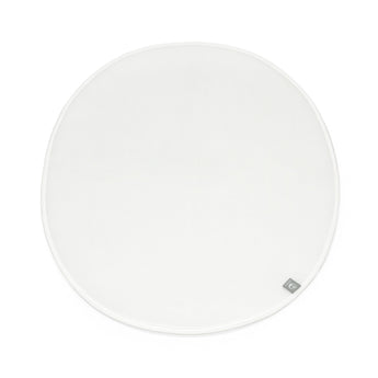 White round Stokke Sleepi Mini polyurethane foam mattress pad with a small gray brand tag.