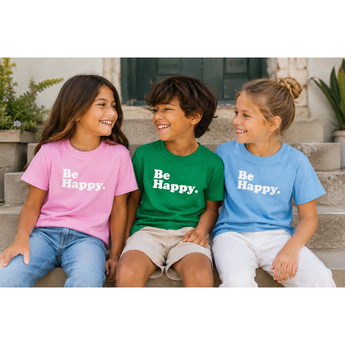 Three children sitting on steps wearing 'Be Happy' t-shirts.