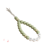 Green teething necklace with name beads on a beige background