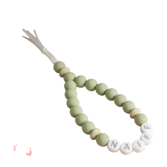 Green teething necklace with name beads on a beige background